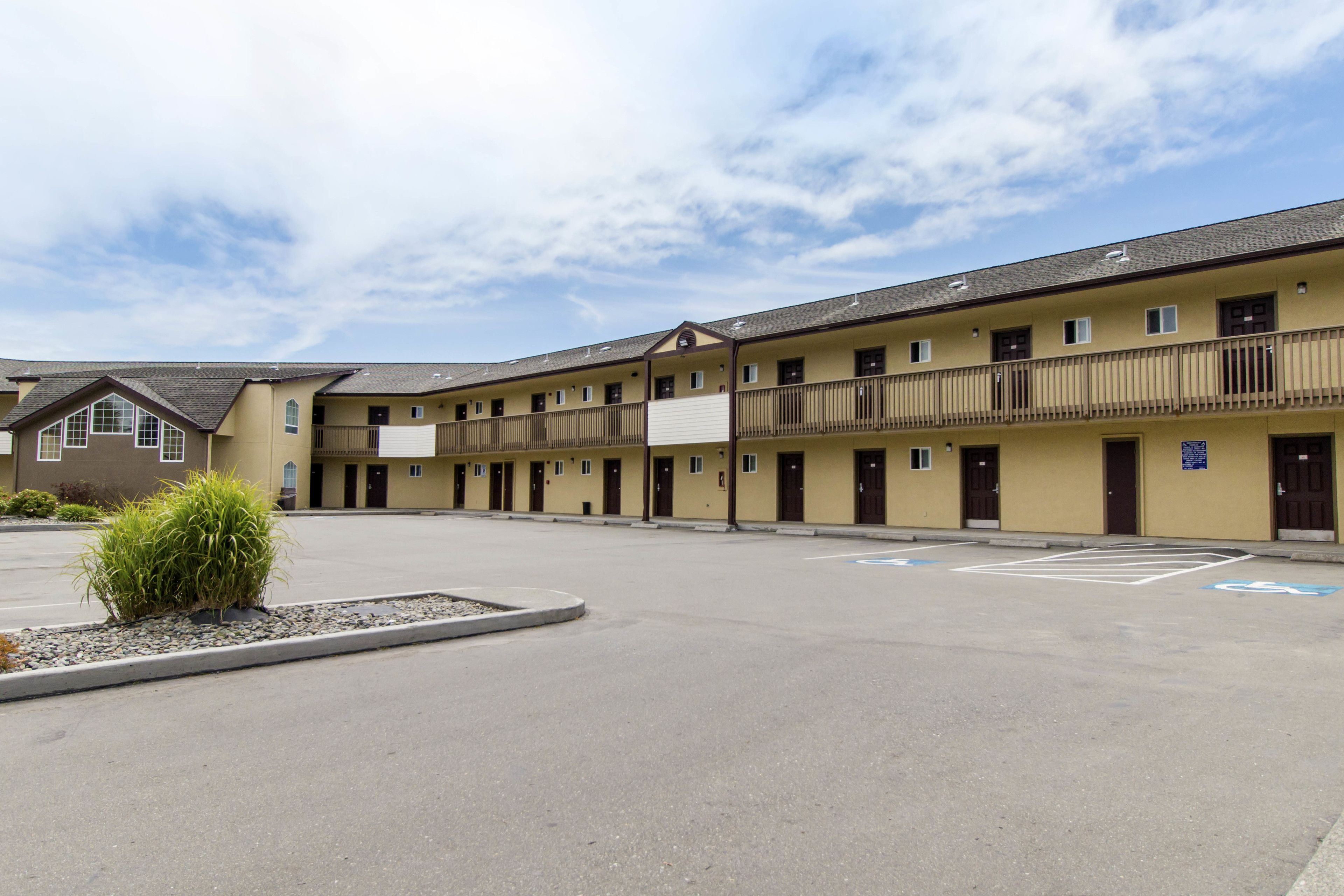Um motel com vários andares e estacionamento em frente.