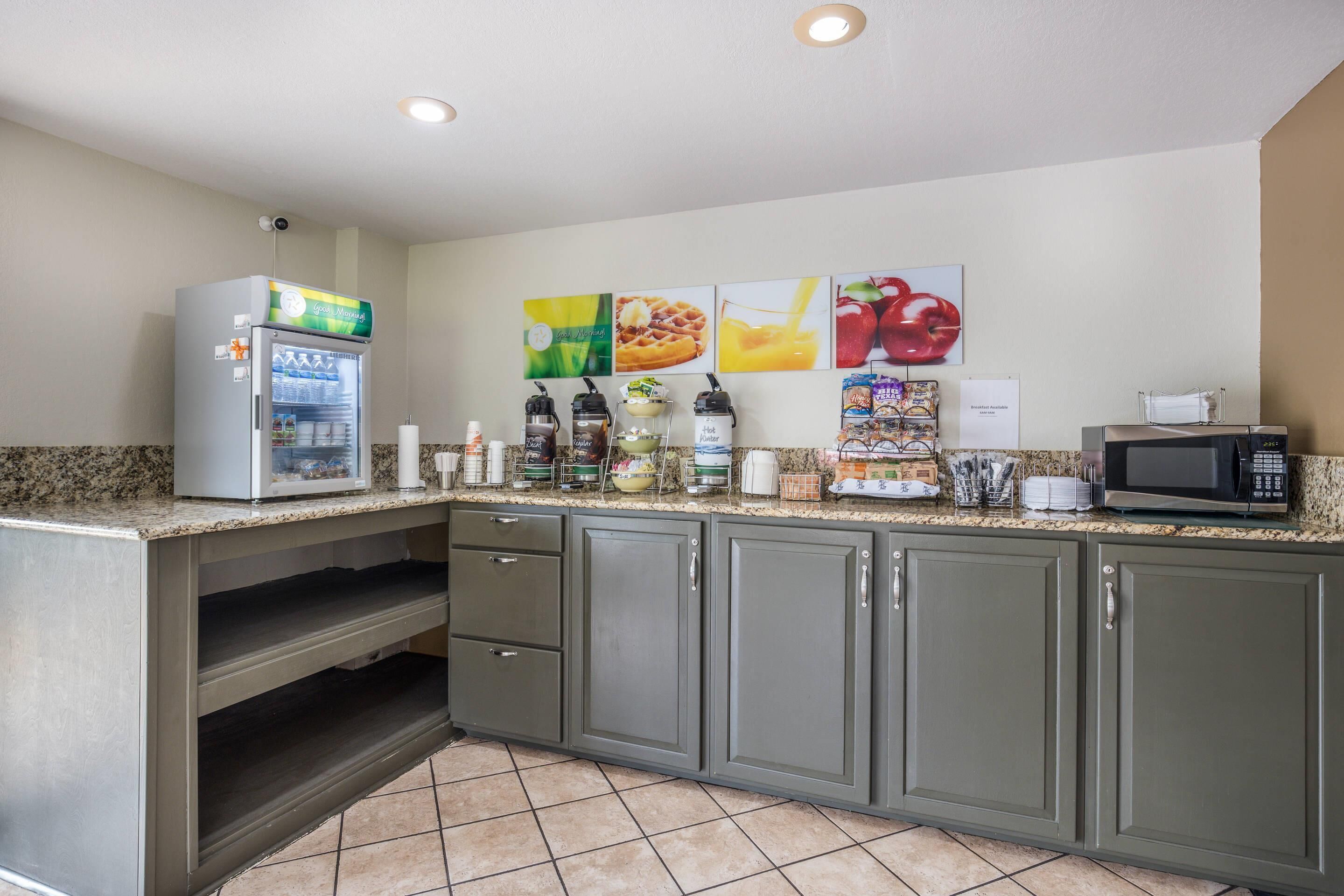 Una kitchenette equipada con refrigerador, microondas, cafetera y diversos alimentos.