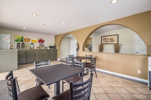 A spacious kitchen with a dining area, featuring a central island, multiple chairs, and a kitchen counter with appliances.