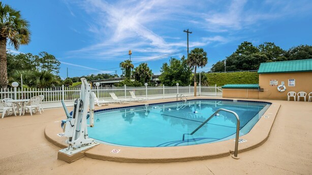 A swimming pool with a lifeguard chair, lounge chairs, and a fenced area.