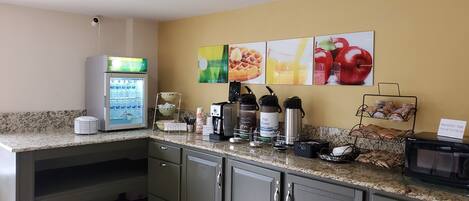 A kitchen with a coffee machine, a kettle, a toaster, and a microwave. There are also several bowls and a coffee maker on the counter.