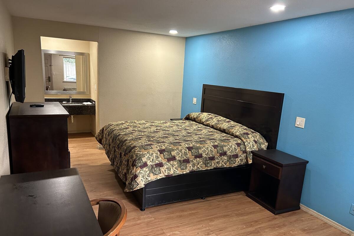 Un dormitorio con cama, escritorio, silla, cómoda y espejo.