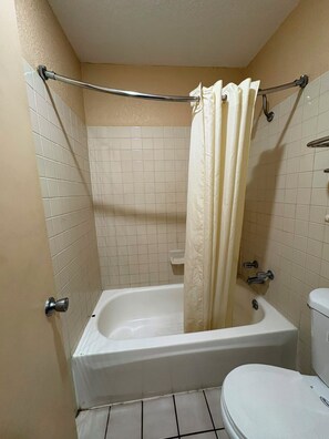 A bathroom with a bathtub, toilet, and a shower curtain. - Blue Star Inn Lafayette Near Airport I-10 (Lafayette)