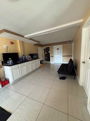 A spacious living area with a kitchen counter, a flat-screen TV, and a sofa. - Blue Star Inn Lafayette Near Airport I-10 (Lafayette)