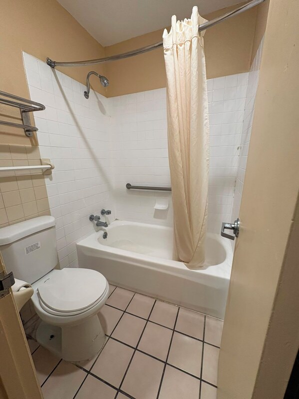 A bathroom with a toilet, bathtub, and shower curtain.