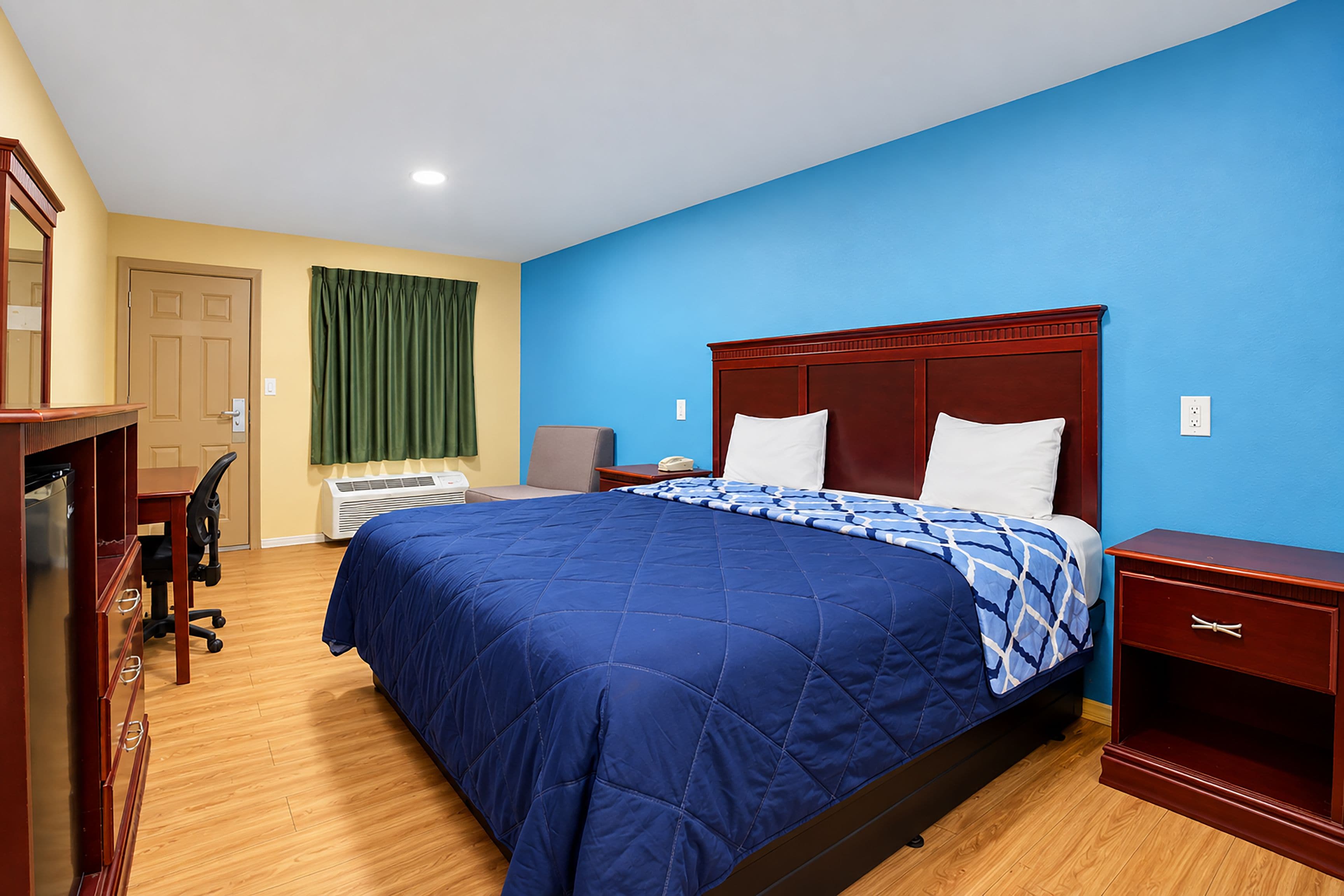 Une chambre d’hôtel avec un grand lit, un bureau et une chaise.