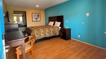 A room with a bed, a desk, and a chair. There is a window and a door.