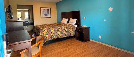A room with a bed, a desk, and a chair. There is a window and a door.