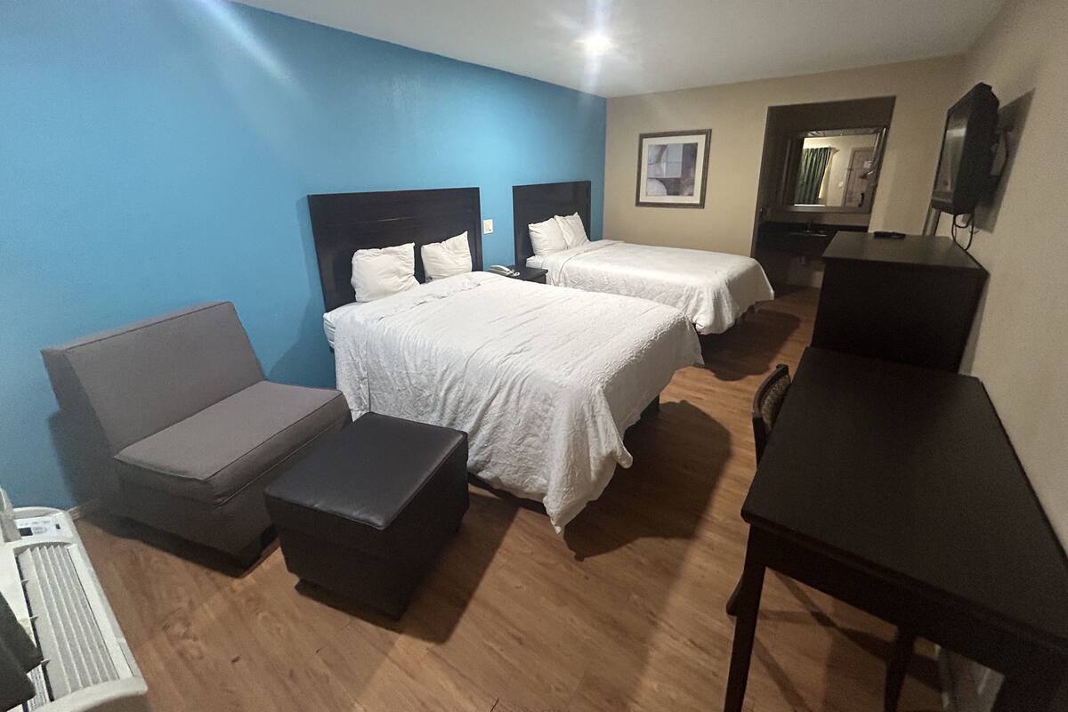 Habitación de hotel con dos camas, un sofá, un escritorio y un radiador.