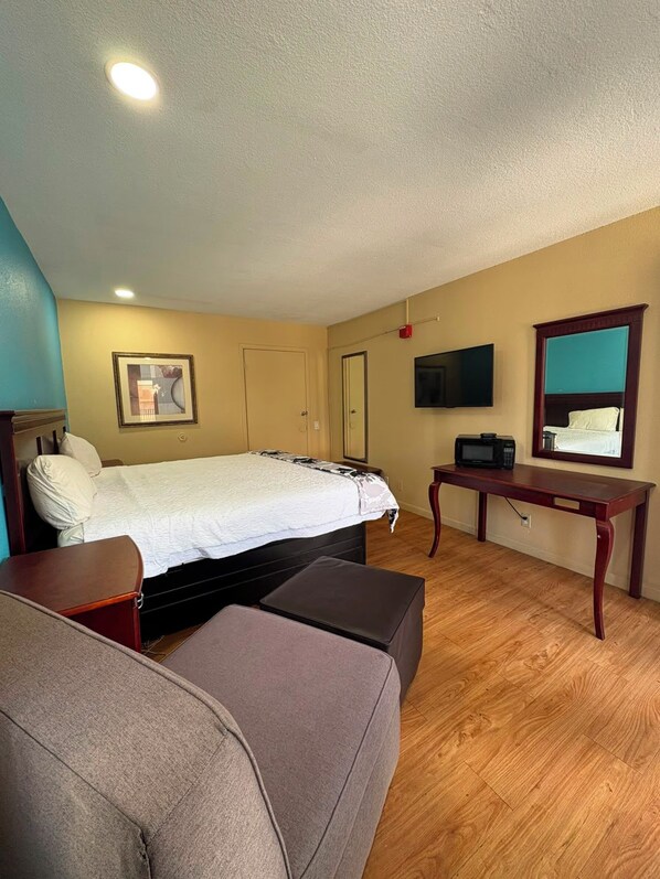 A bedroom with a bed, a television, a desk, and a couch.