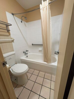 A bathroom with a toilet, bathtub, and shower curtain. - Blue Star Inn Lafayette Near Airport I-10 (Lafayette)