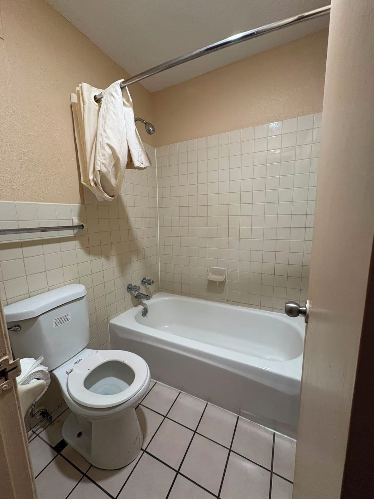 A bathroom with a toilet, a bathtub, and a towel rack.