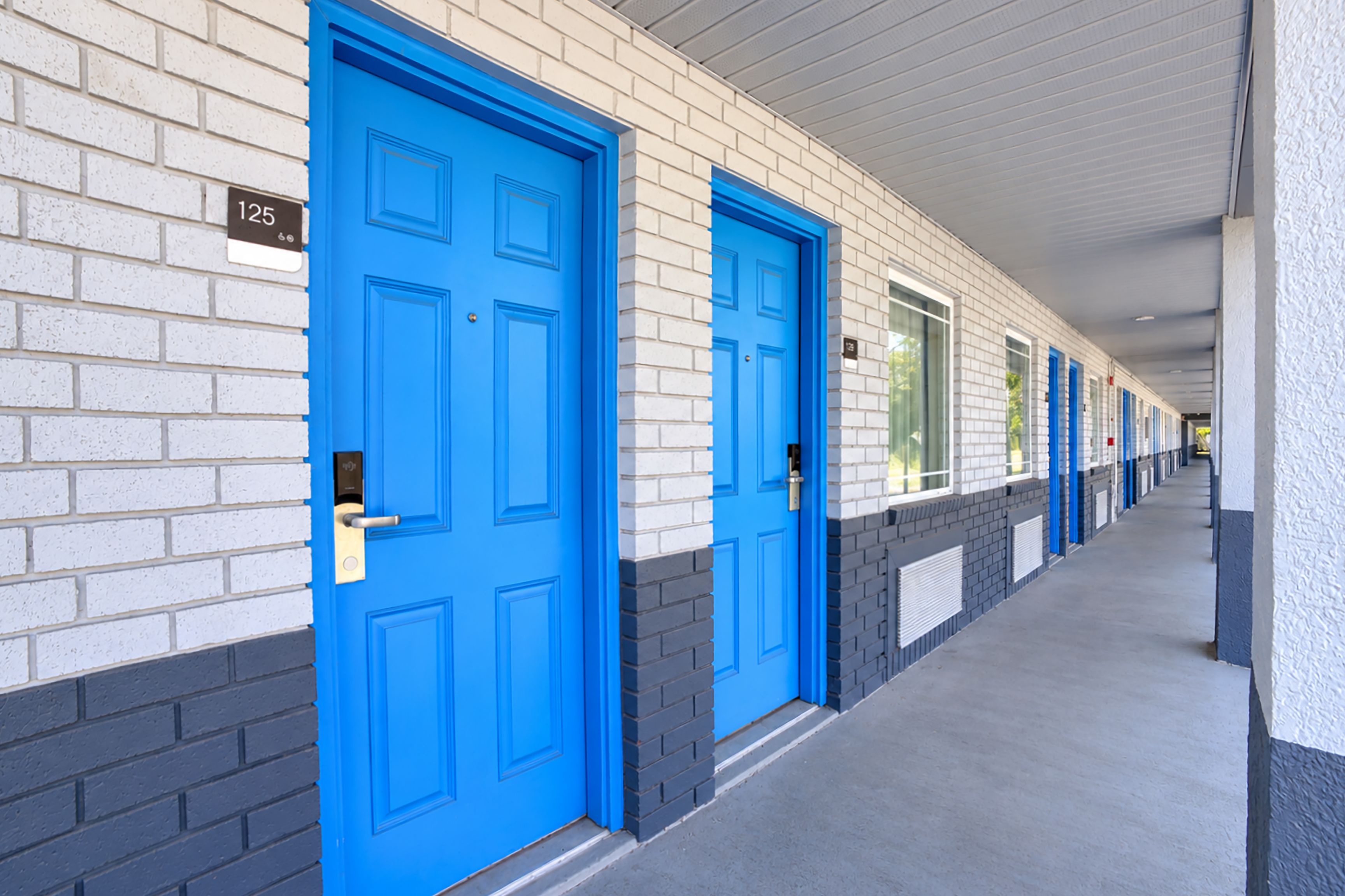 Un couloir avec des portes bleues, numérotées de 125, qui donnent sur des chambres individuelles.
