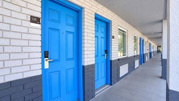 Un couloir avec des portes bleues, numérotées de 125, qui donnent sur des chambres individuelles.