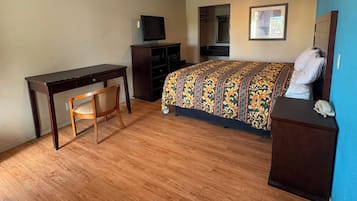 A bedroom with a bed, a desk, a chair, a television, and a telephone.