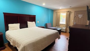 Una habitación de hotel con una cama grande, un escritorio, una silla y un aparador.
