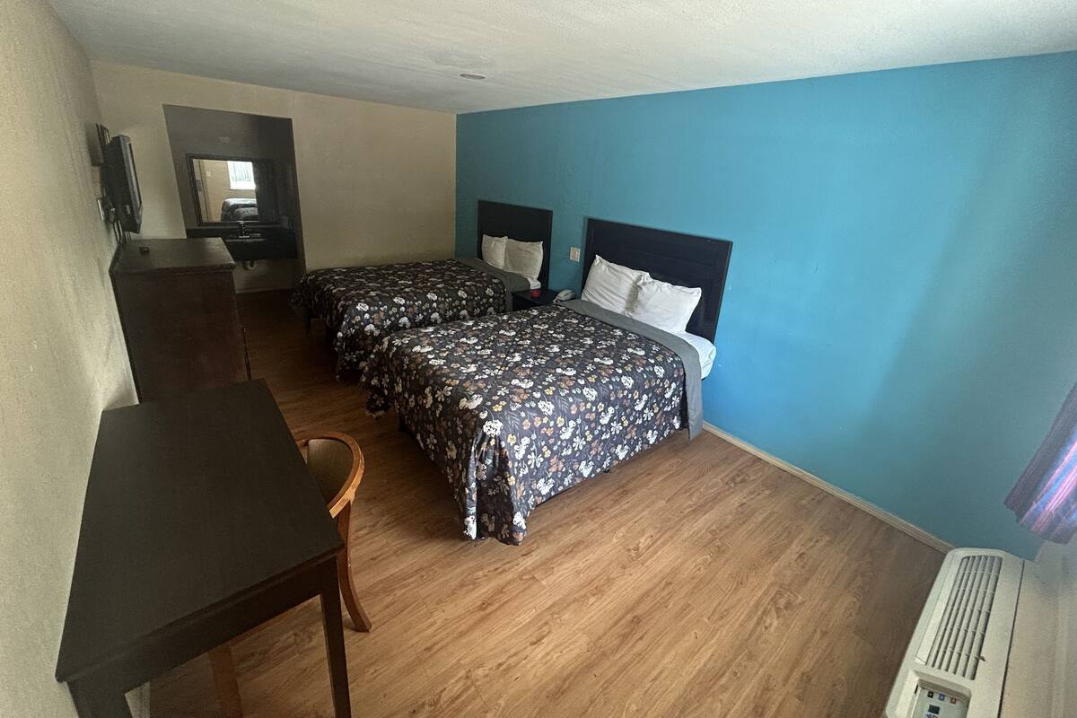Una habitación con dos camas, un escritorio y una silla.