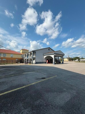 A building with a covered entrance, a parking lot, and a clear sky. - Blue Star Inn Lafayette Near Airport I-10 (Lafayette)