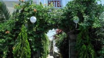 A hotel entrance with a stone archway, potted plants, and flags.