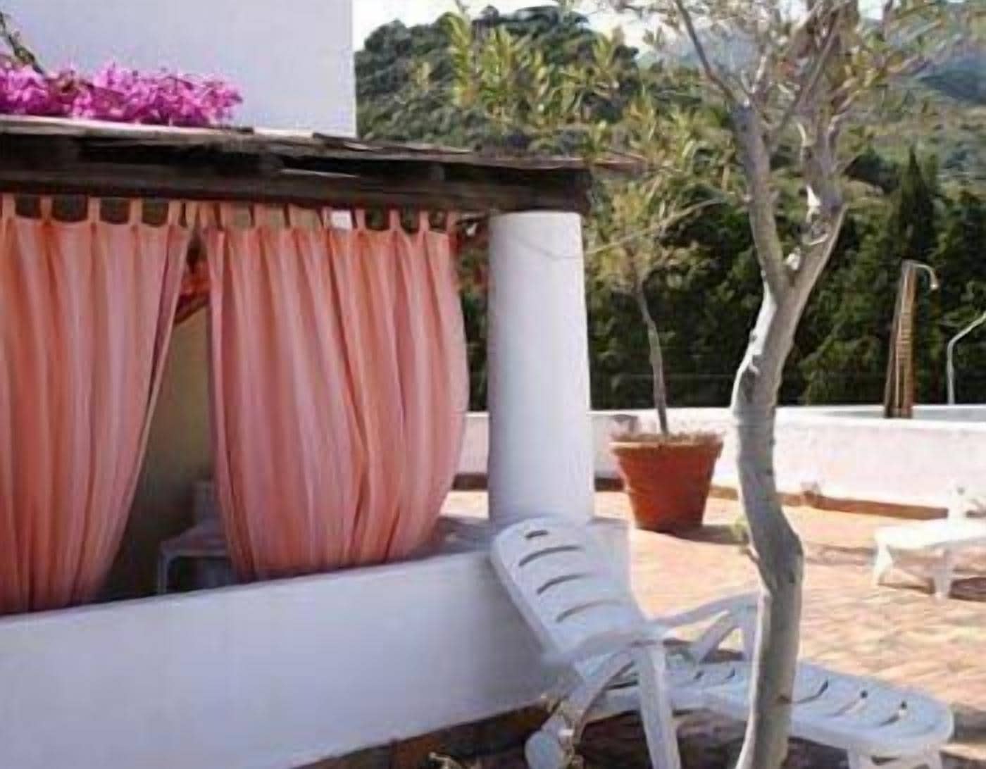 A covered outdoor seating area with a white chair and a potted plant.