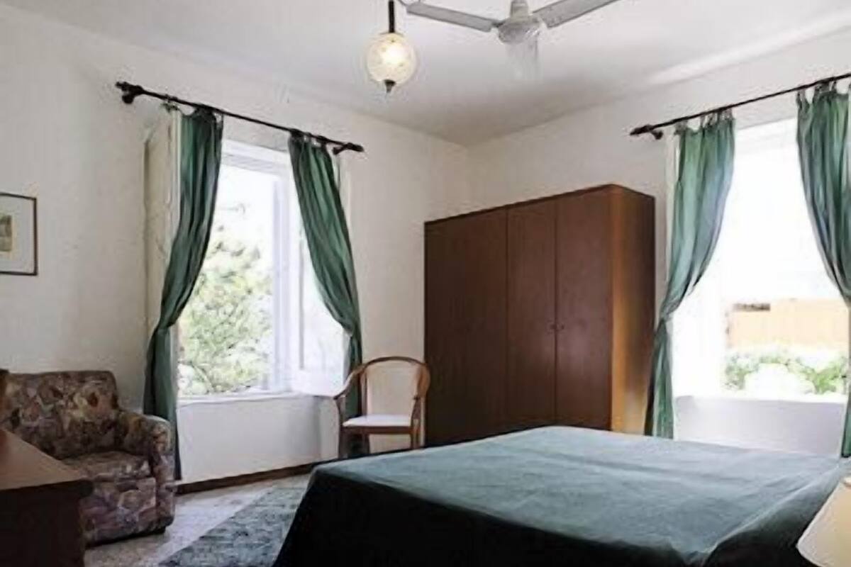 Ein Schlafzimmer mit Bett, Stuhl, Kleiderschrank und Schreibtisch mit Lampe.