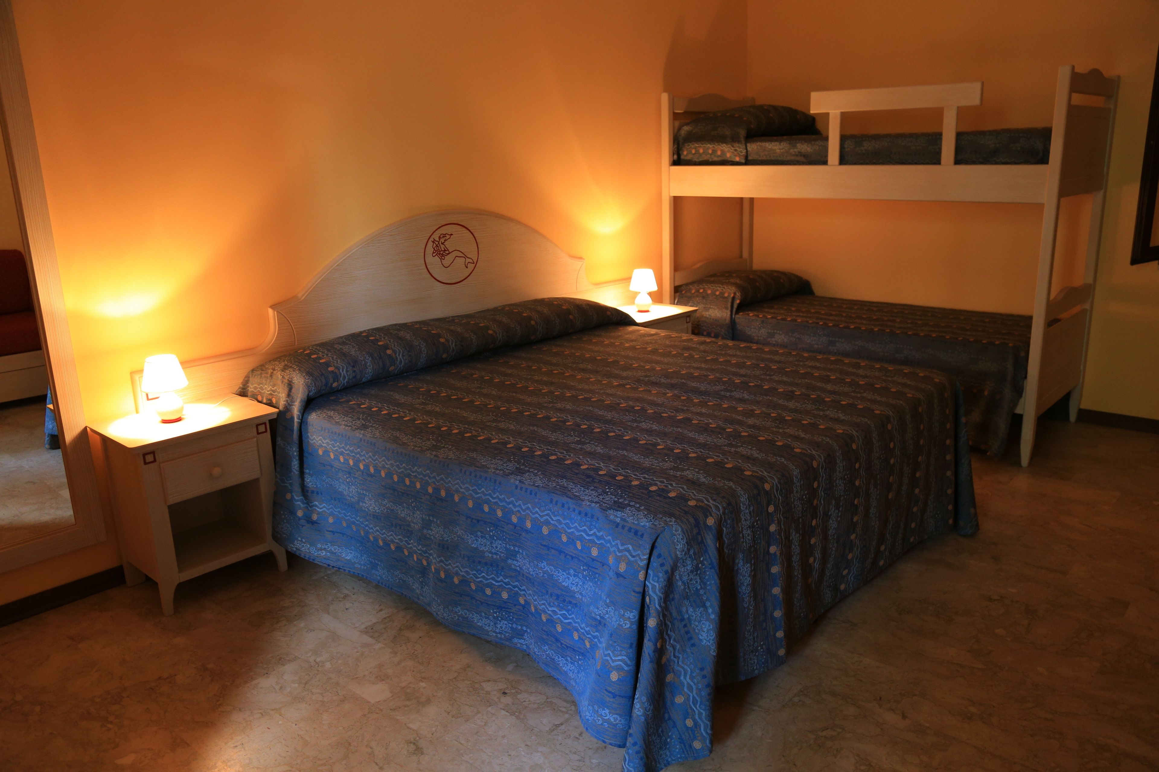 Une chambre avec deux lits, chacun doté d’une tête de lit et d’une table de chevet avec une lampe.