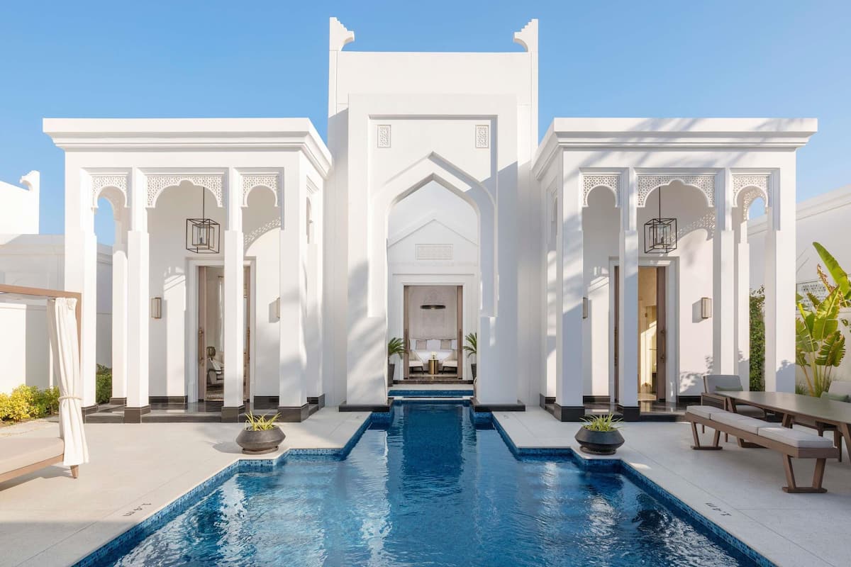 A pool area with a central pool and two symmetrical wings, each with a door and a small balcony.
