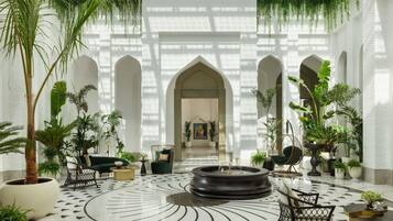A spacious lobby with a central fountain, surrounded by seating and potted plants, under a high ceiling with natural light.