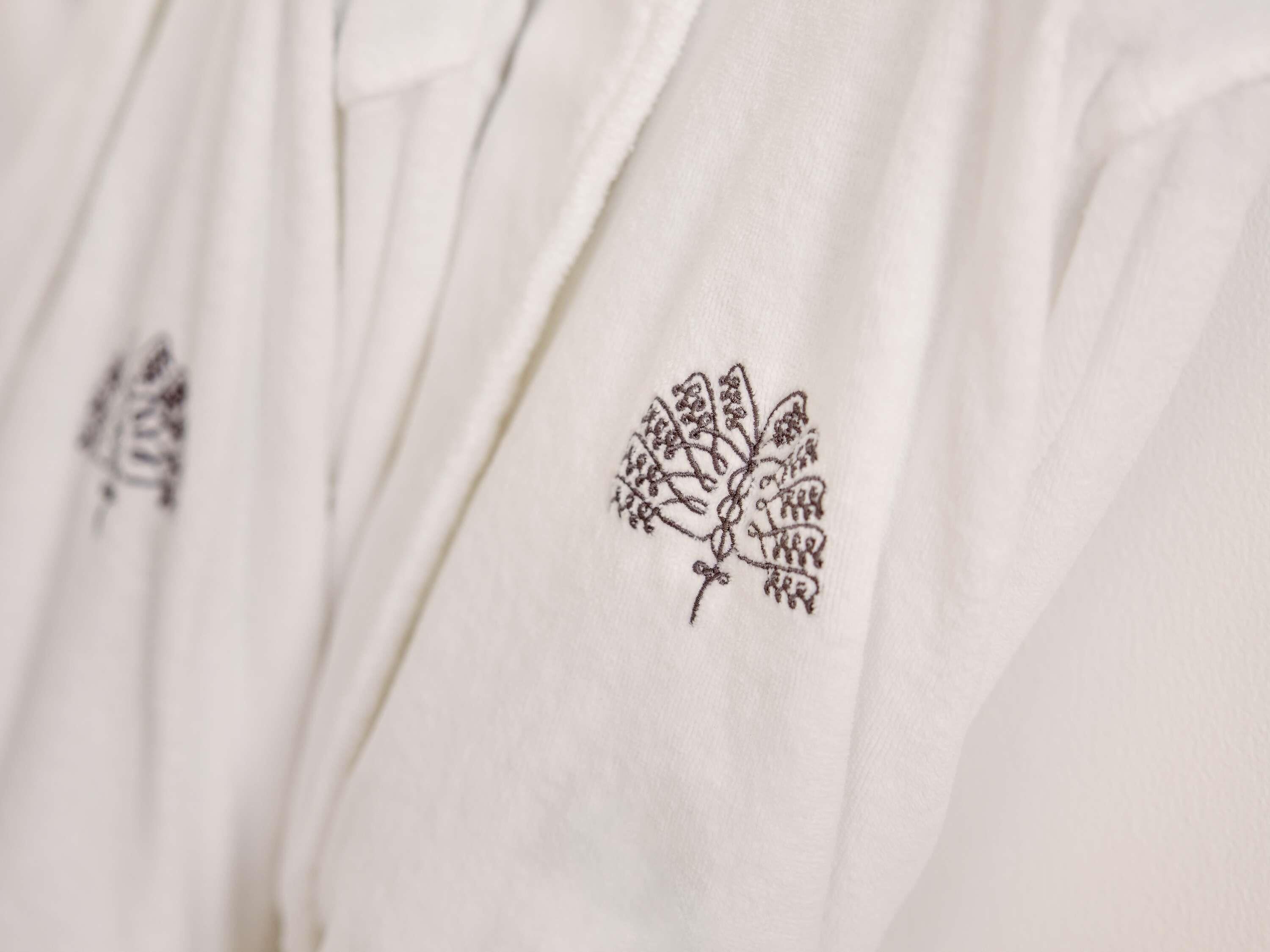 A white garment with a detailed embroidered design on the shoulder.