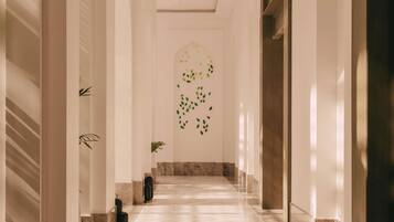 A hallway with marble flooring, white walls, and a decorative wall art.