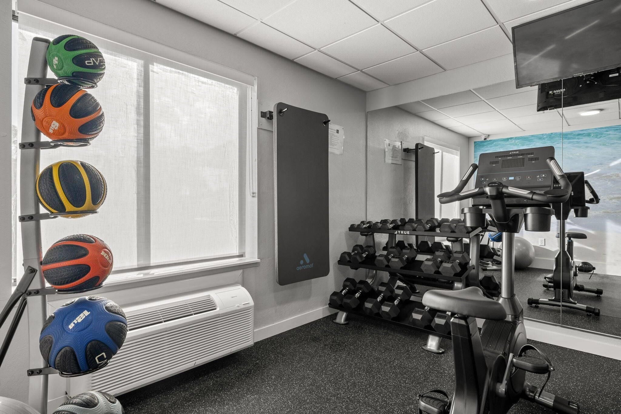 Un gimnasio con equipo de ejercicio, una ventana y un espejo.