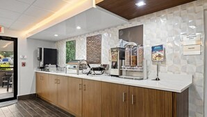 A modern kitchen area with a coffee station, a microwave, and a food display. - Clarion Pointe Lakeland I-4 (Lakeland)