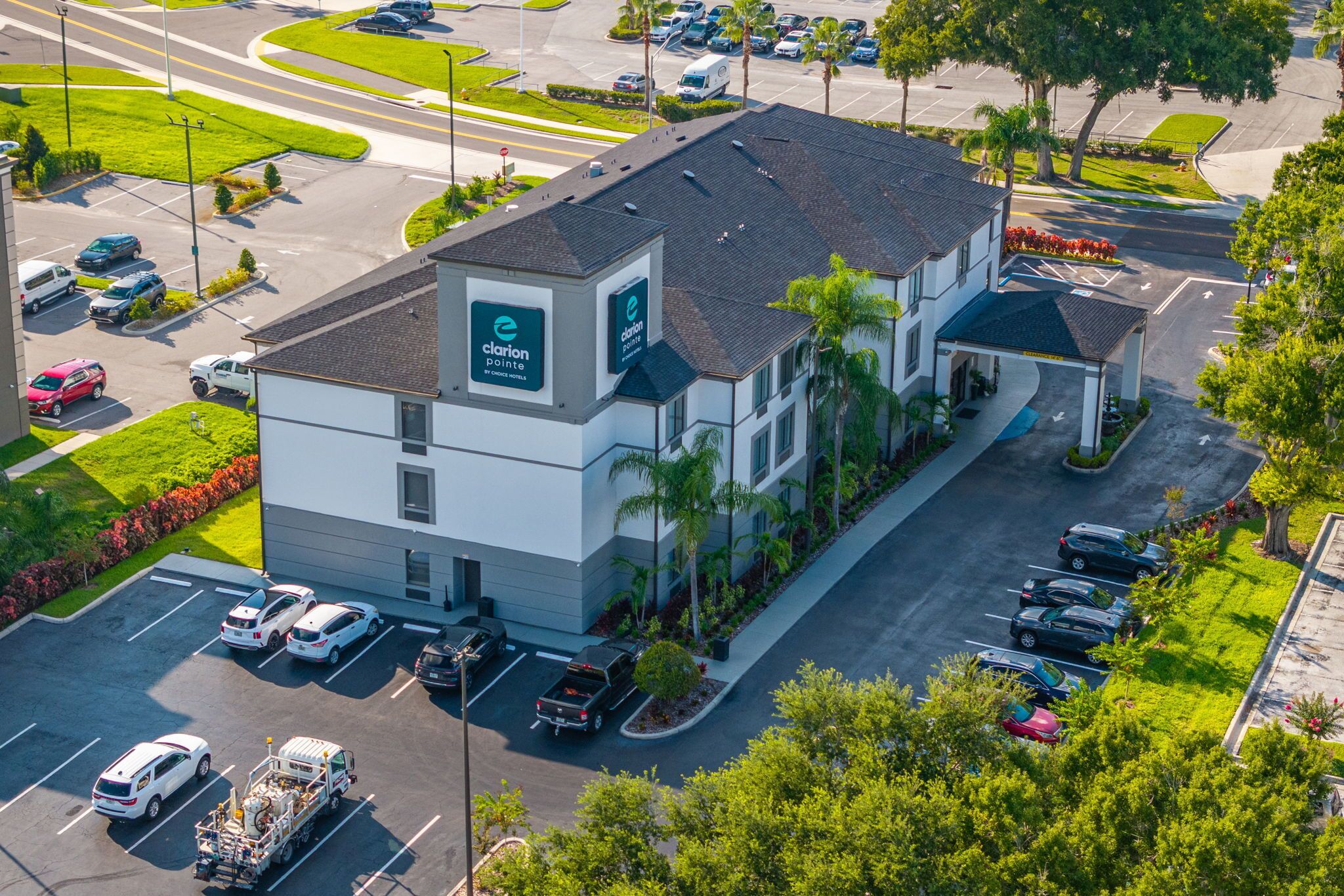 A modern building with a parking lot, a covered area, and a green lawn.