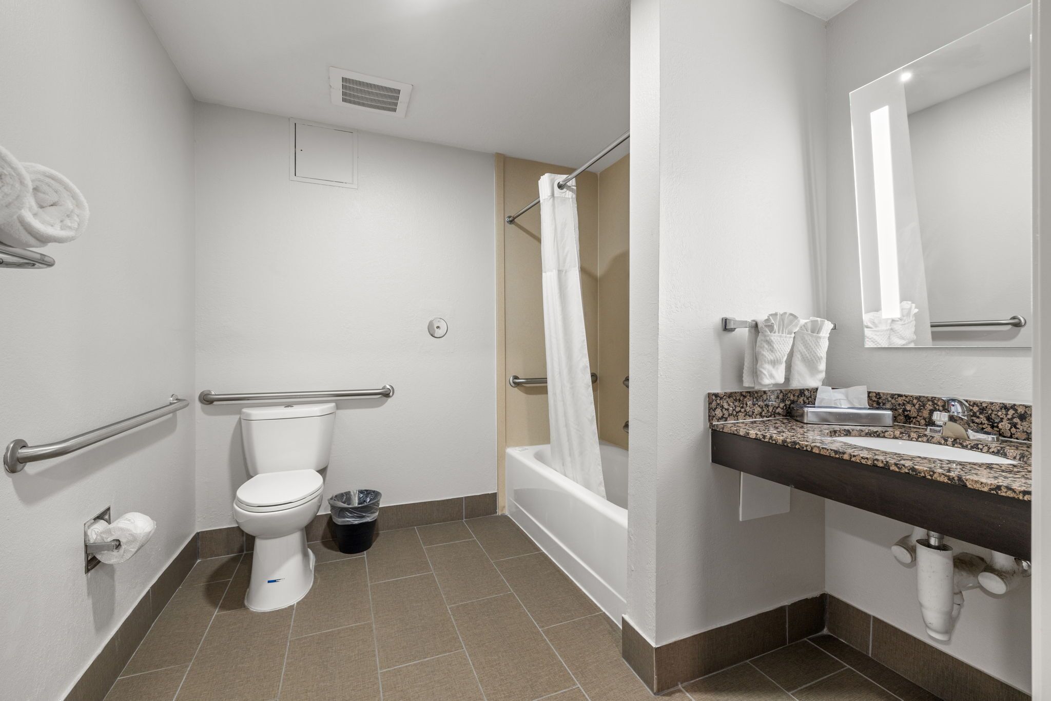 A modern bathroom with a toilet, shower, and sink.