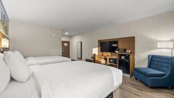 A hotel room with two beds, a desk with a chair, a TV, and a coffee machine.