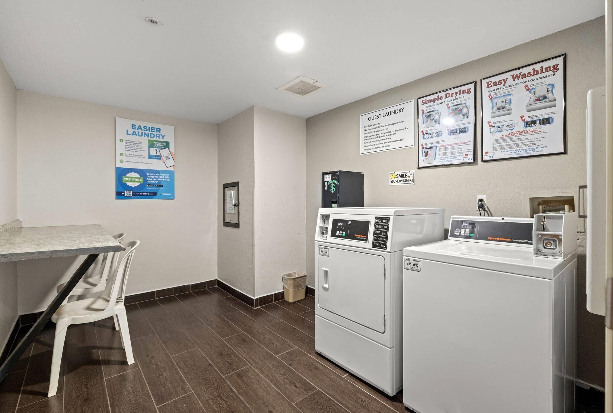 A laundry area with two washing machines, a table, and chairs.