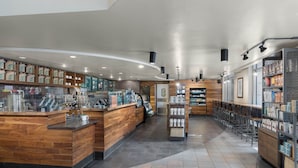 A modern coffee shop interior with wooden counters, a variety of coffee machines, and shelves stocked with coffee products. - The Westin Arlington (Arlington)