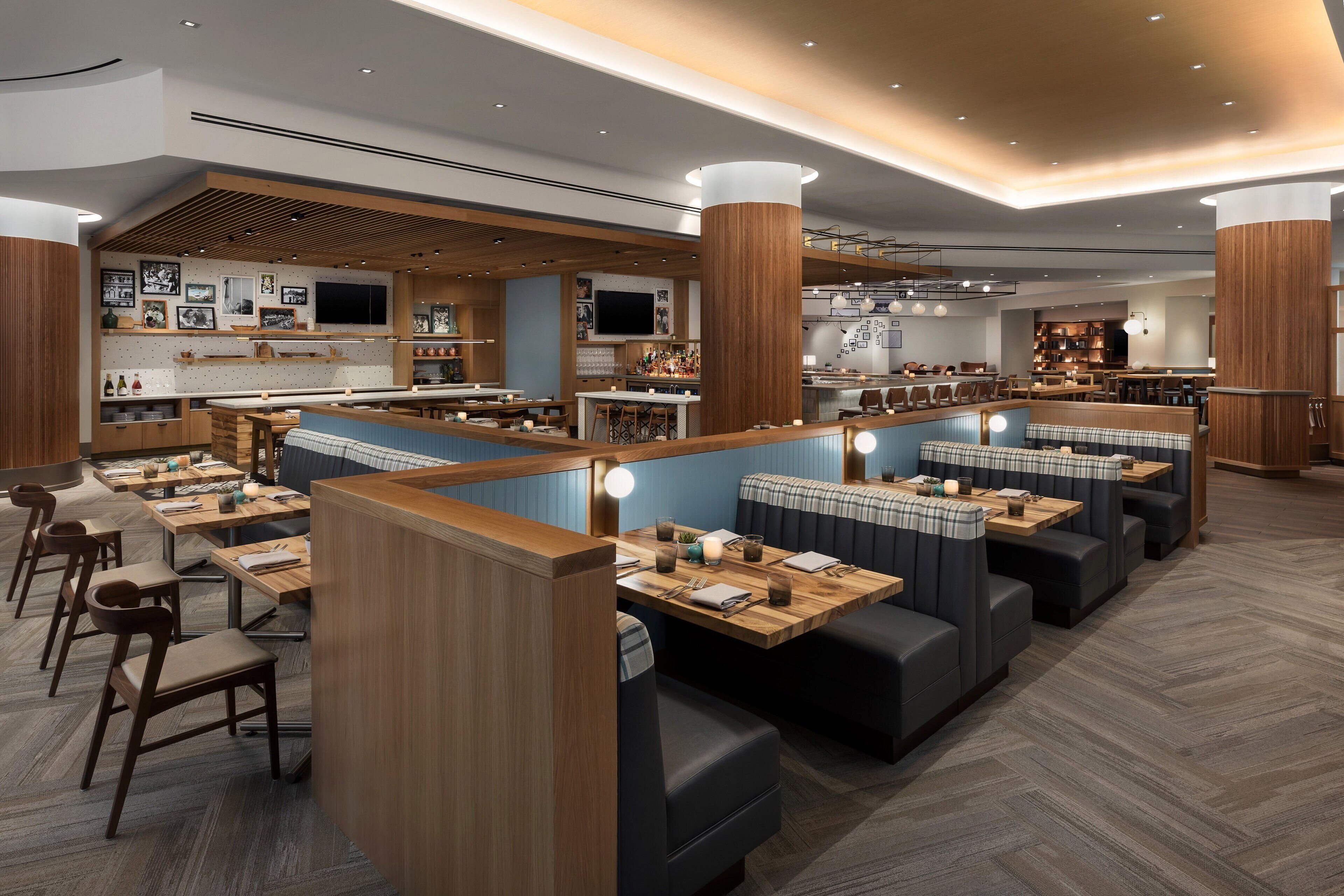 Un restaurante moderno con detalles de madera, cabinas y una zona de bar.