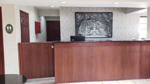 A reception area with a wooden reception desk, a framed black and white photograph on the wall, and a restroom sign. - Inn at Mulberry Grove (Port Wentworth)