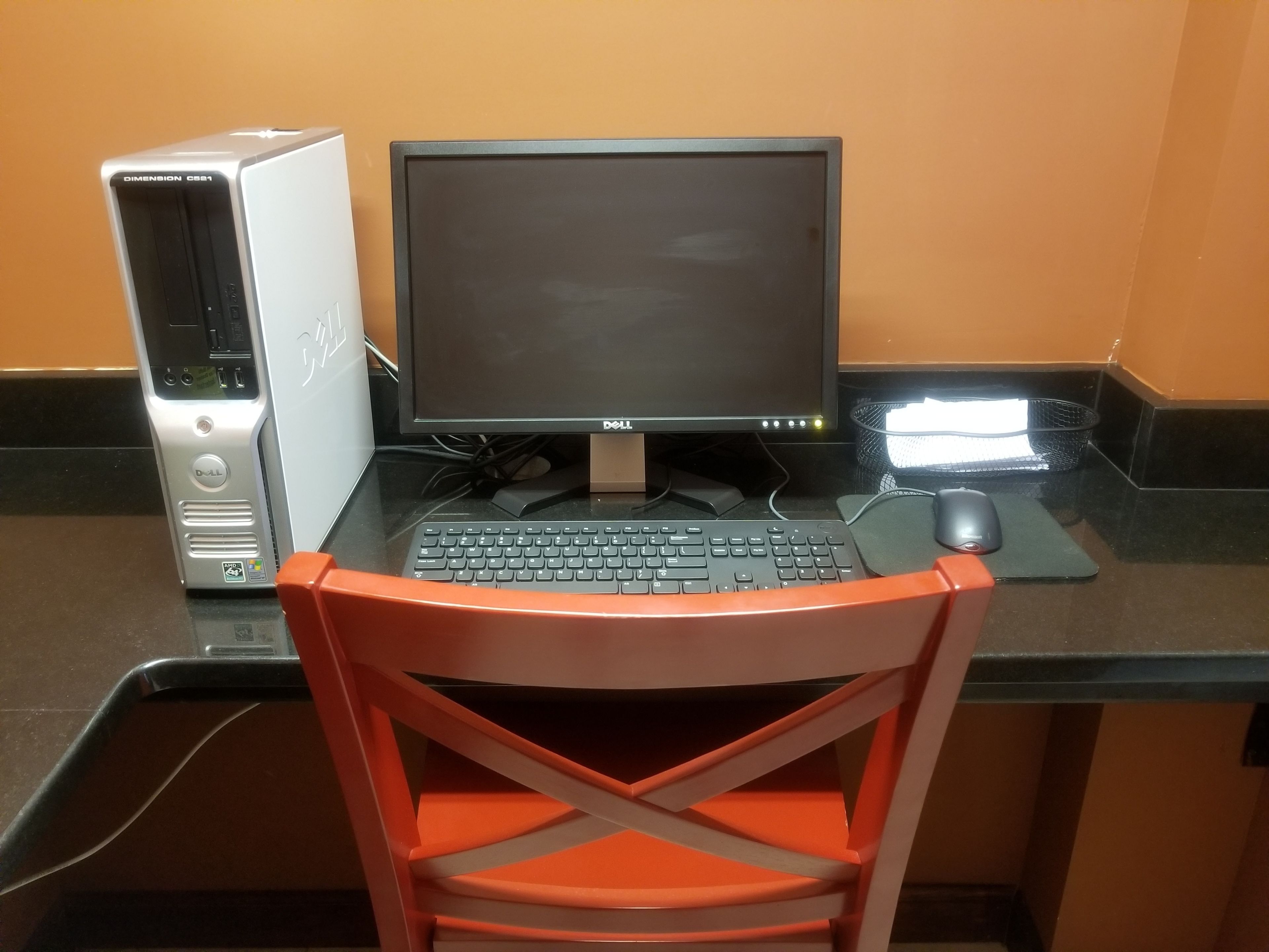 A computer desk with a monitor, keyboard, and mouse.