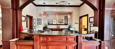 A reception area with a marble counter, wooden paneling, and framed certificates on the wall.