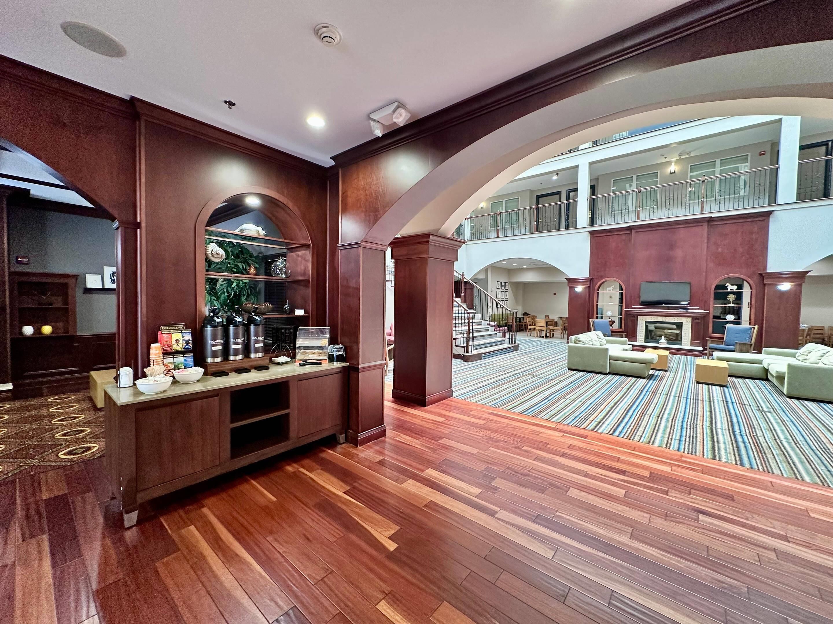 Un'ampia hall con una reception in legno, un angolo caffè e un'area relax con divani e un braciere.