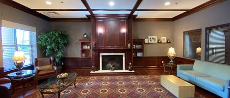 A spacious living room with a fireplace, wooden paneling, a patterned carpet, and a comfortable seating area.