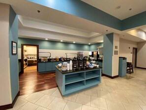 A modern kitchen with a central island, white cabinets, and a blue accent wall.
