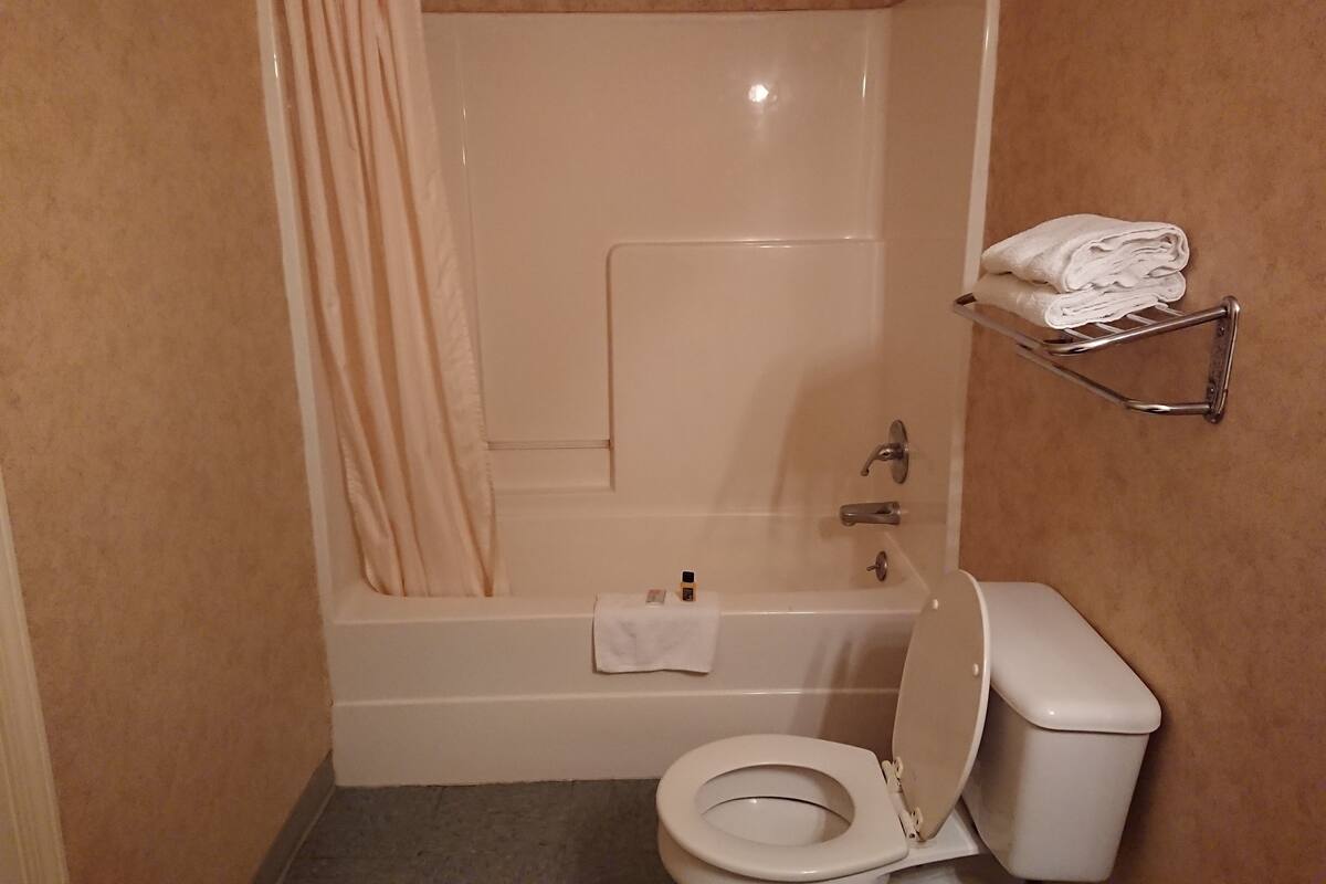 A bathroom with a bathtub, toilet, and a towel rack.