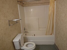 A bathroom with a bathtub, toilet, and shower curtain.
