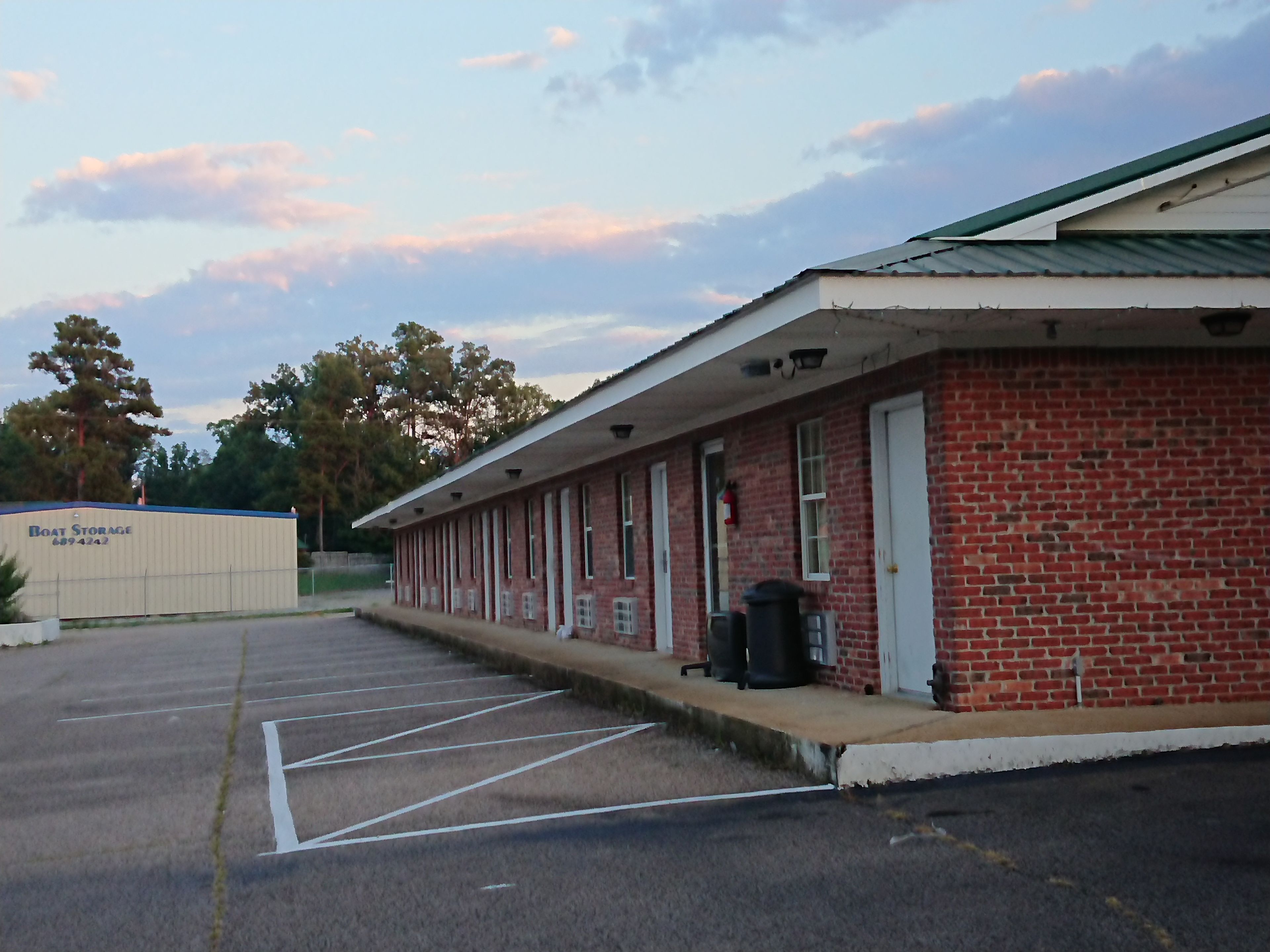 A brick building with a row of rooms and a covered outdoor area.