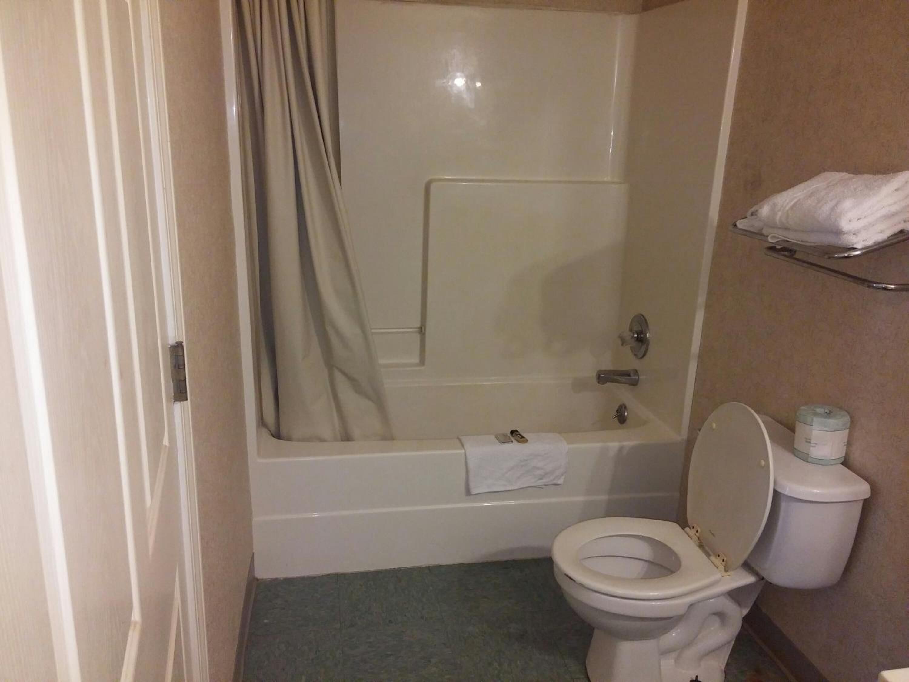 A bathroom with a bathtub, toilet, and a towel rack.