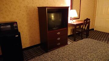 Habitación de hotel con televisión, escritorio y una silla.