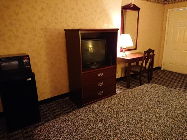 A hotel room with a television, a desk, and a chair.